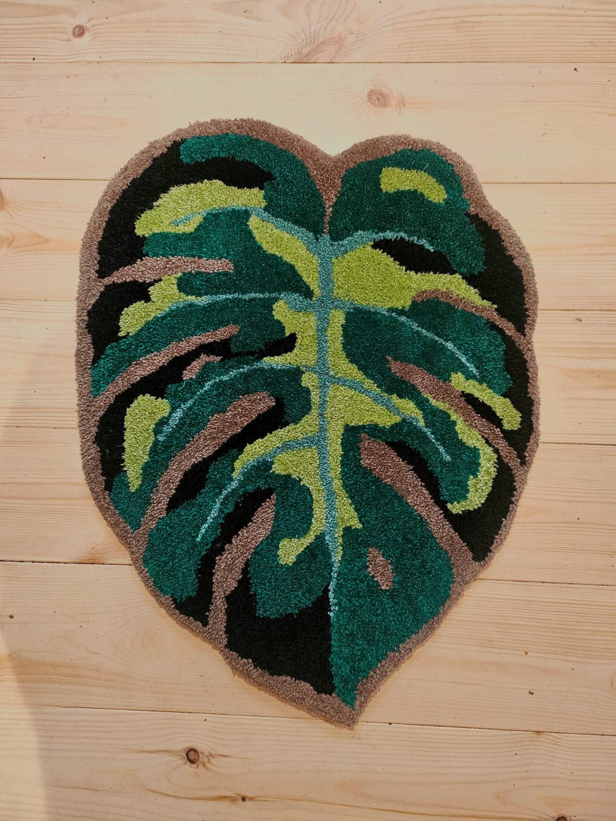 hand tufted rug in the shape of a green leaf.